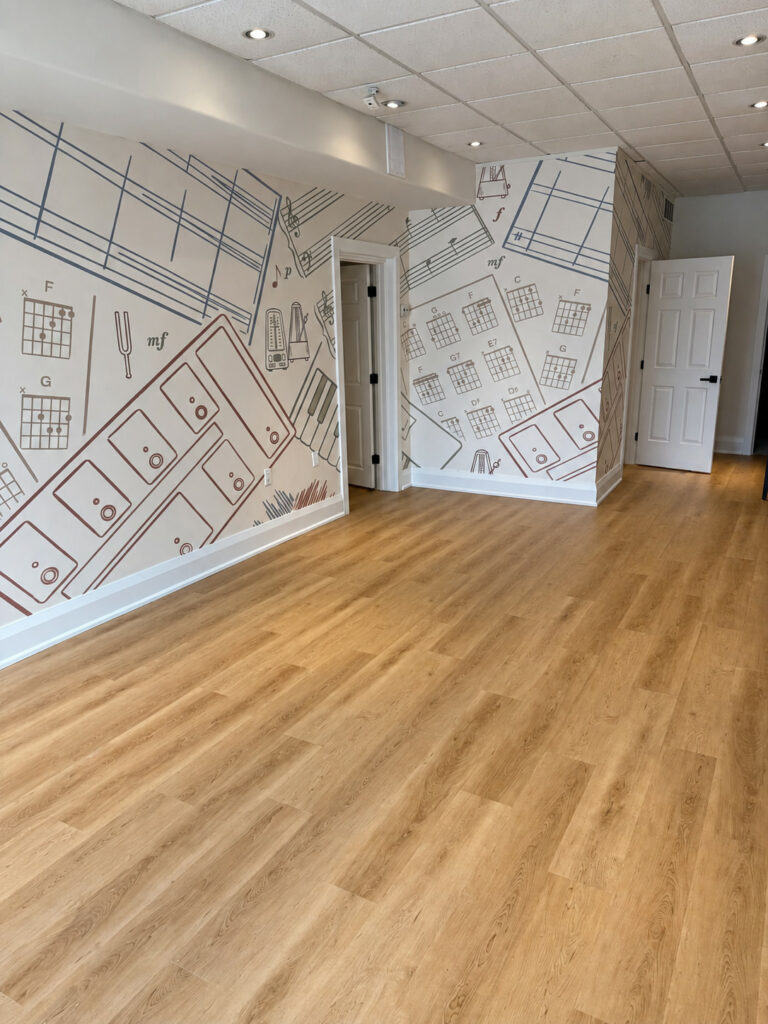 Wood look plank flooring in a music studio with chord chart and sheet music murals on the walls
