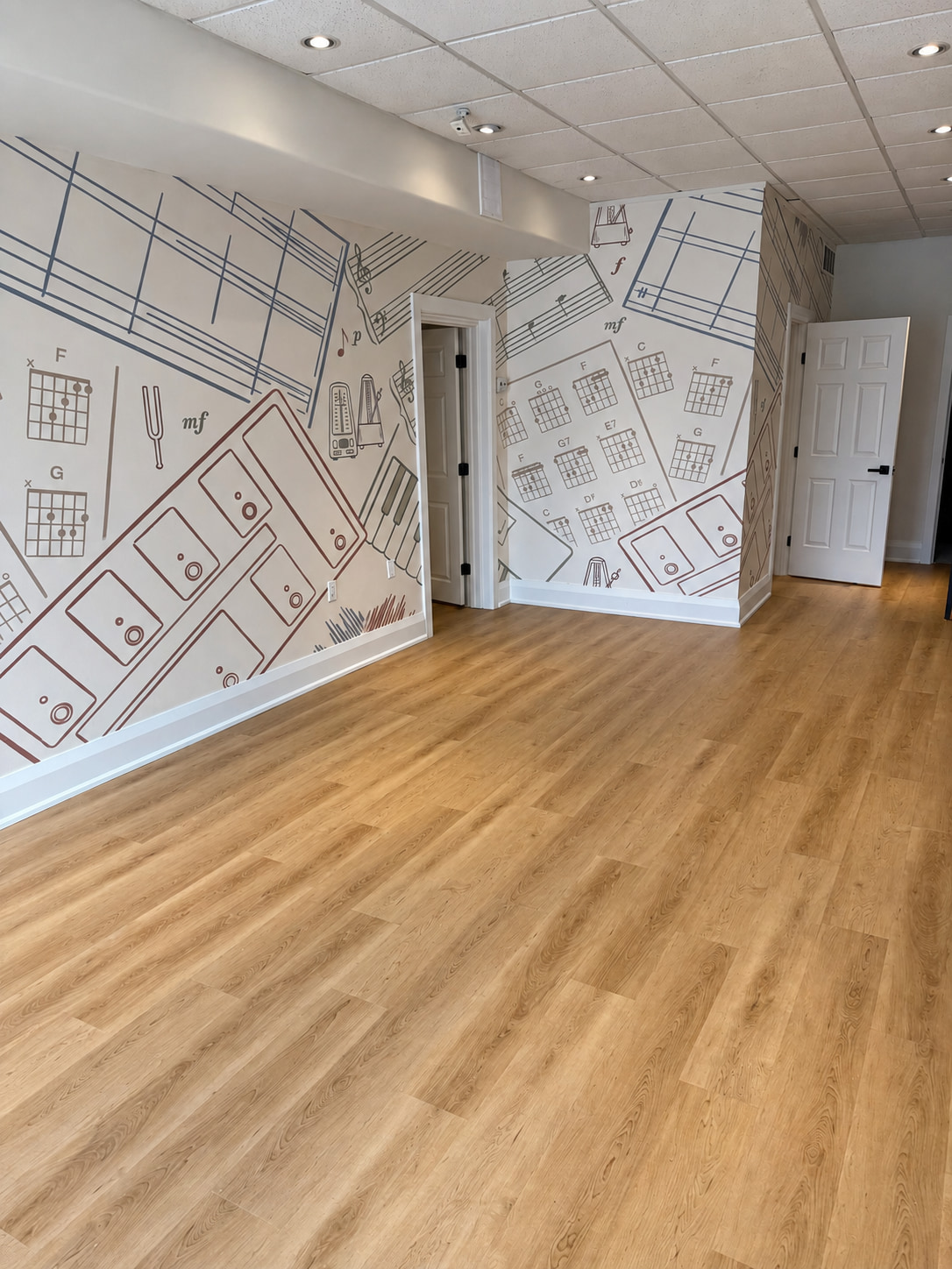 Wood look plank flooring in a music studio with chord chart and sheet music murals on the walls