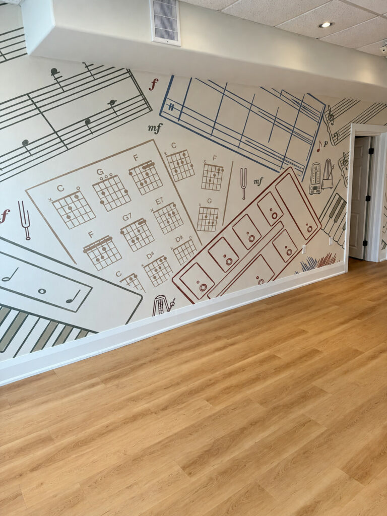 Chord chart and sheet music mural above wood look plank flooring and white baseboards