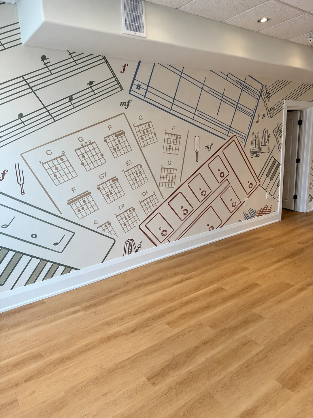 Chord chart and sheet music mural above wood look plank flooring and white baseboards