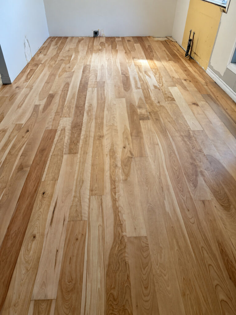 Newly installed natural hardwood with mixed light and dark boards in a room still under renovation