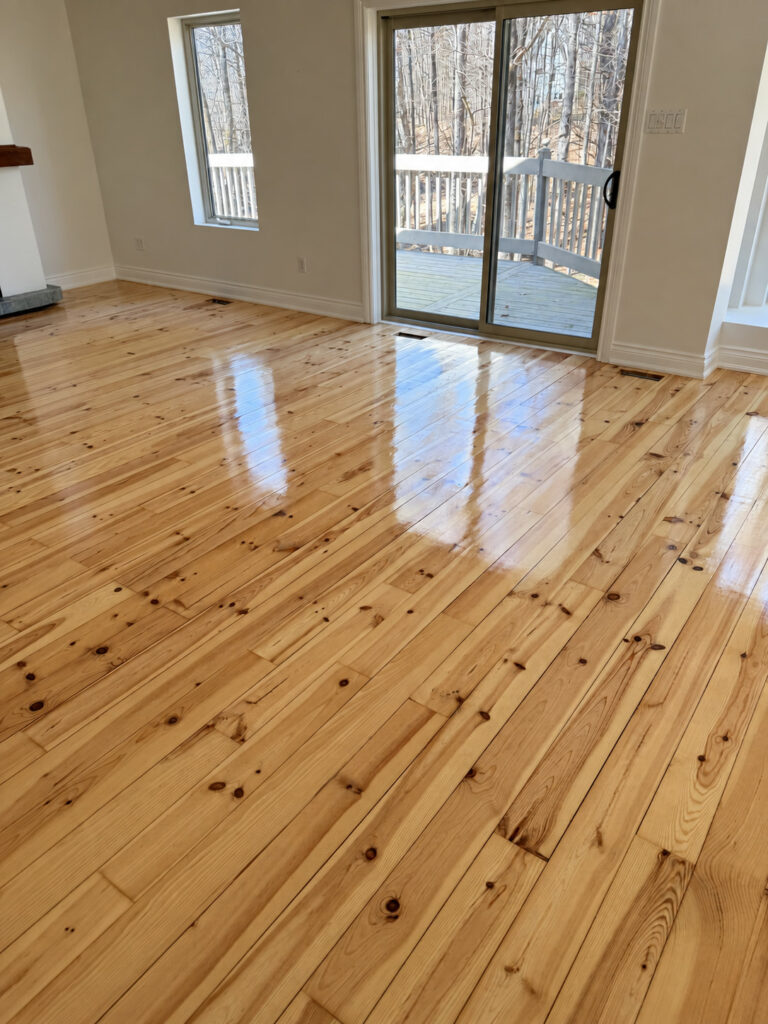 High gloss knotty pine floor in a bright room with sliding patio doors to a deck