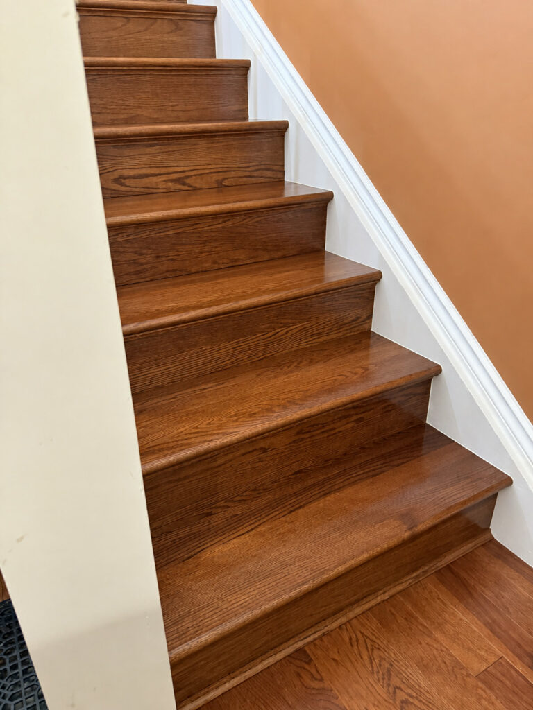Stained oak stair treads and risers between a white skirt board and a warm painted wall