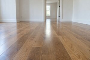 Newly installed warm oak hardwood floor in an empty room, free of construction dust, with a doorway leading to a second room