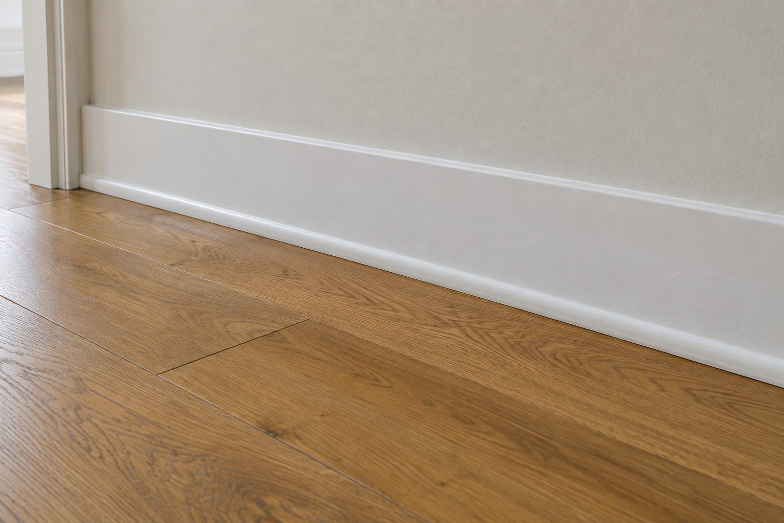 Shoe moulding along a white baseboard covering the gap at the edge of a hardwood floor