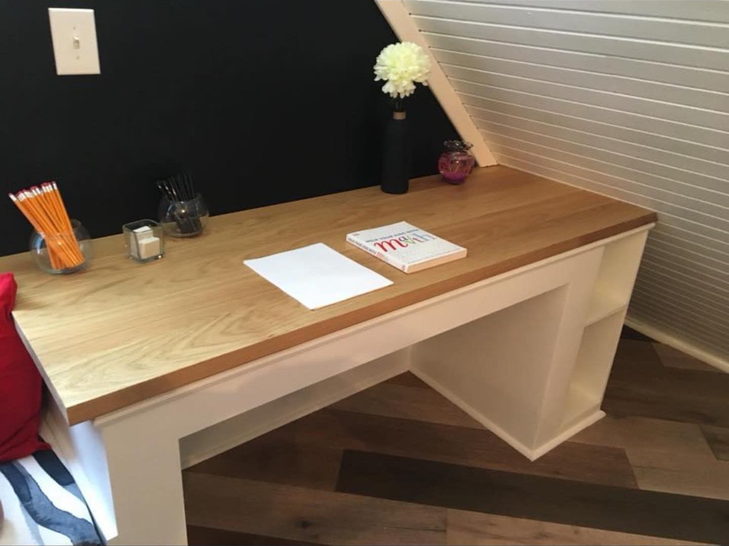 Built-in wood-top desk under a sloped white plank ceiling