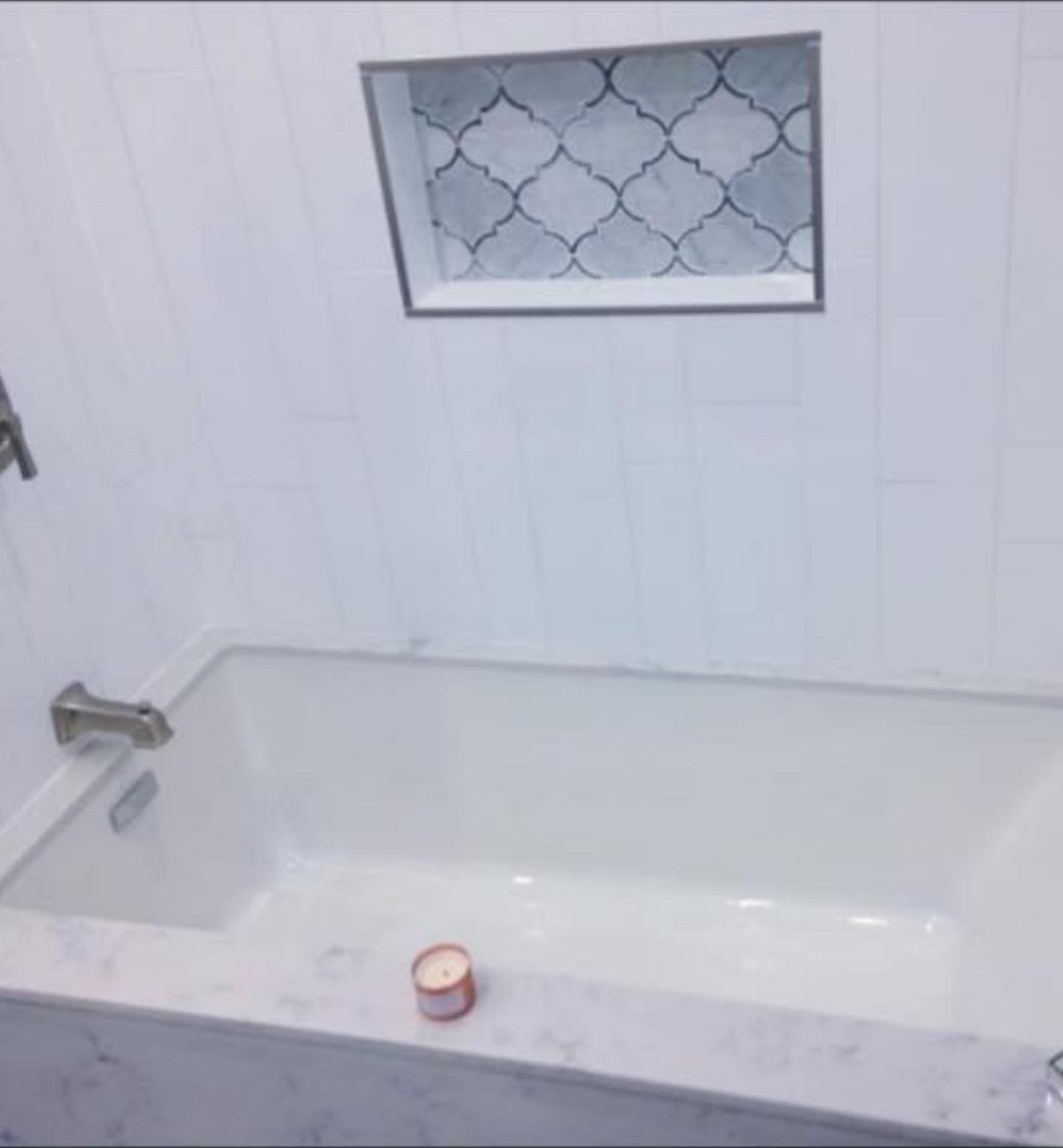 Soaker tub with a marble-look tile surround and an arabesque tile niche